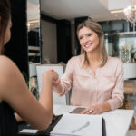 Dwie kobiety w salonie beauty umawiające wizyte i ścikające dłonie.